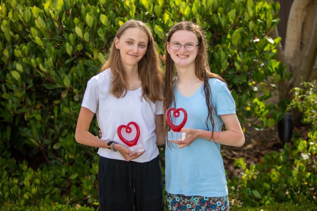 Faith Frazier (left) holding the Teen with a Heart award at the 2022 Conference along with friend and fellow teen council member Katie Dammann (right).