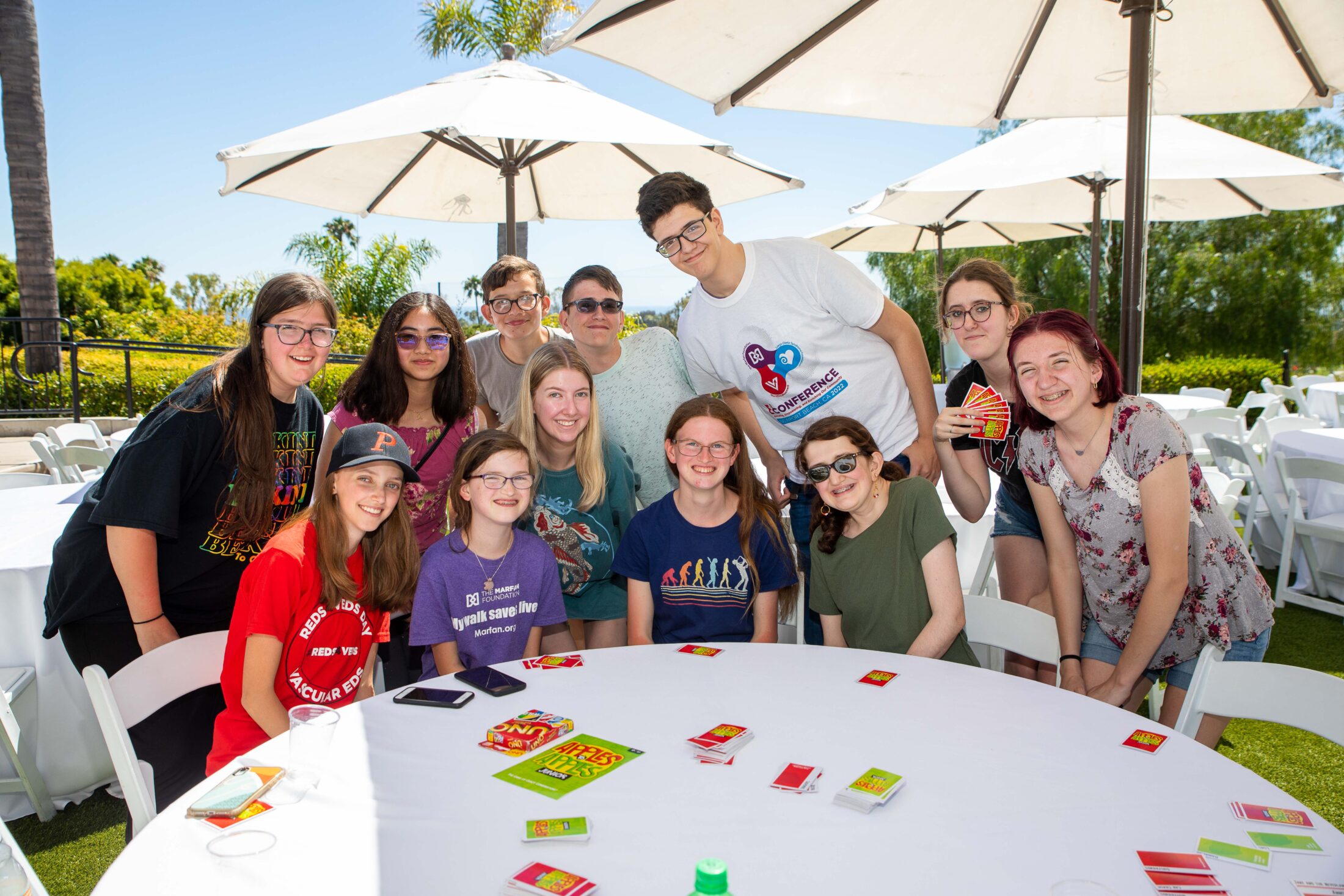 Teens gatthered together under sun umbrellas at the 2022 Conference in Southern California.