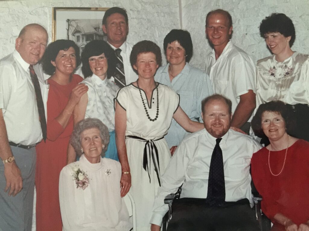 The Wakats with their Mom in later years in a color photo. They are pictured as a group smiling in dressy attire at a family gathering.