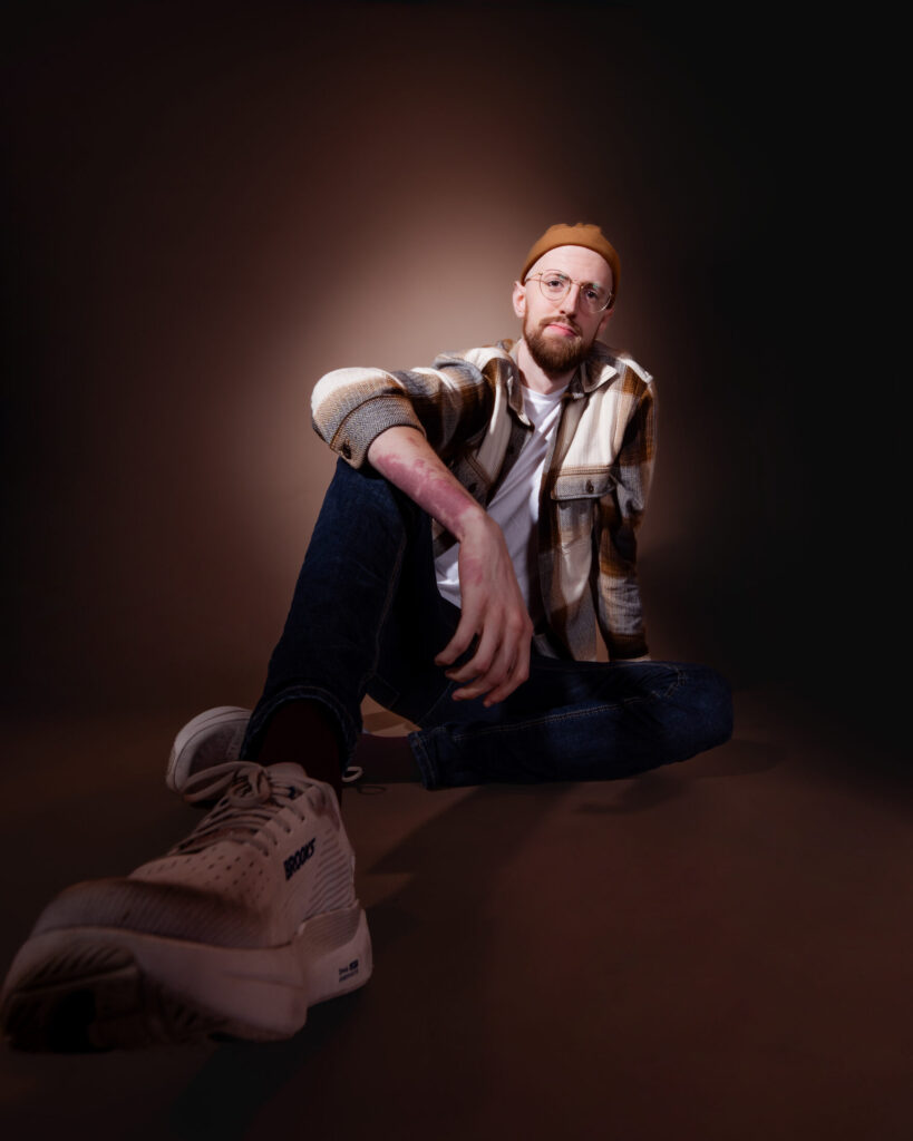 Comic and Marfan Foundation community member Liam Nelson seated and dressed casually in an image as he competes on Star Search