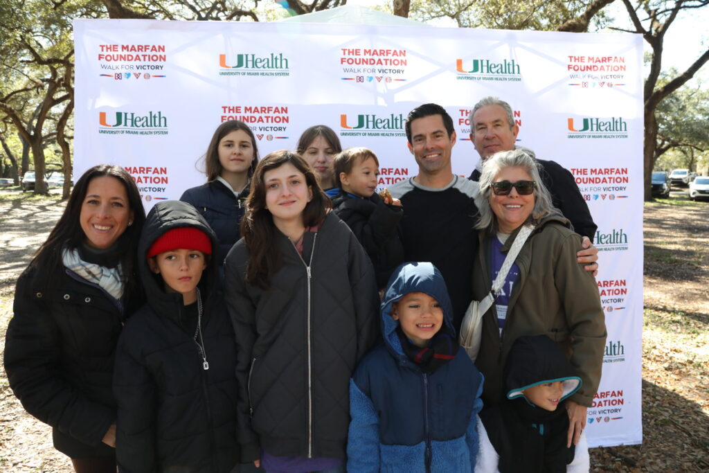 Group team picture in front of logo sign at South Florida Walk for Victory 2026.