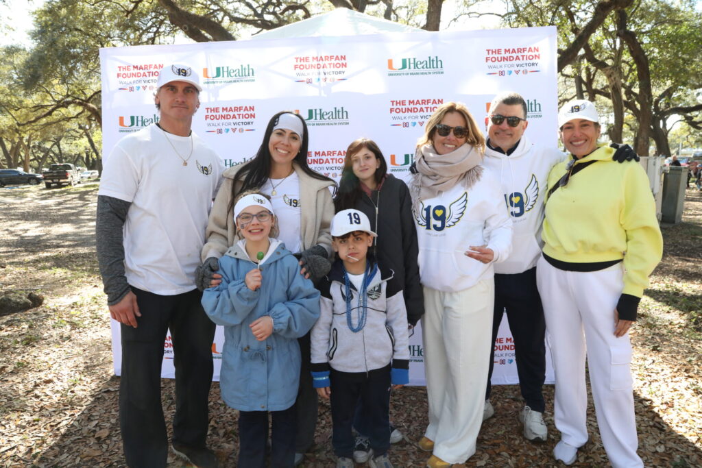 Osuna family and Haley together in front of logo banner at Walk for Victory.