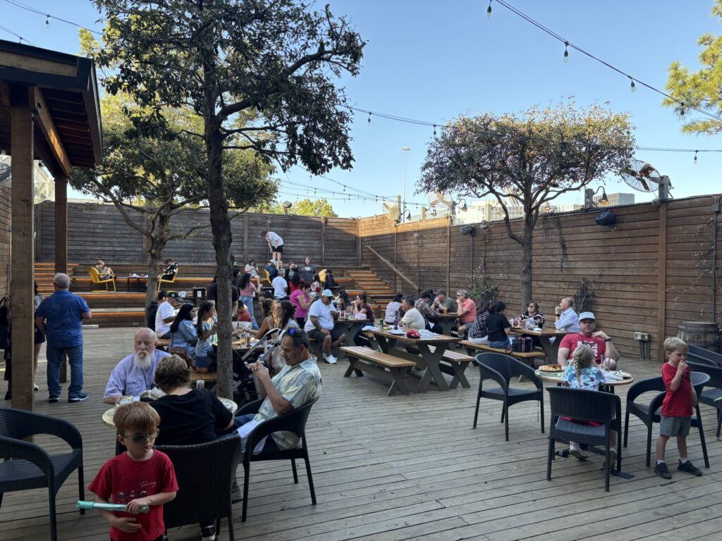 VEDS Party, Houston 2026. People in red shirts sit in casual outdoor restaurant setting. 