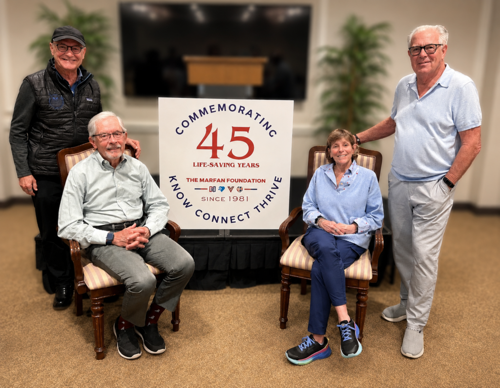Seated Dr. Reed Pyeritz and wife Jane Tumpson, smiling. Flanked by Dr. Kim Eagle left and Michael Weamer right. Image captured during Winter Board 2026. All smiling.