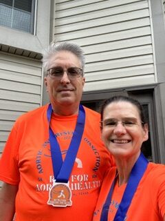 Chris and Heidi Underwood are seen smiling wearing matching shirts and medals
