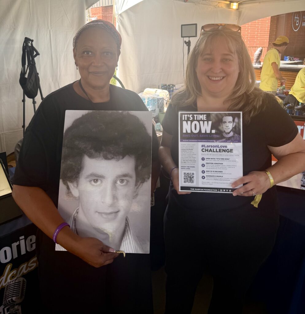 Fredi Walker-Browne is pictured holding Jonathan Larson's headshot alongside April Dawn Shinske holding a #LarsonLove Awareness Sign