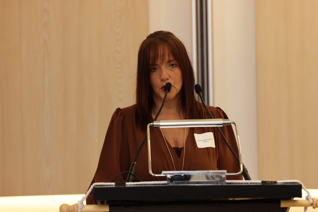 Una integrante de la comunidad habla desde un podio durante el simposio.