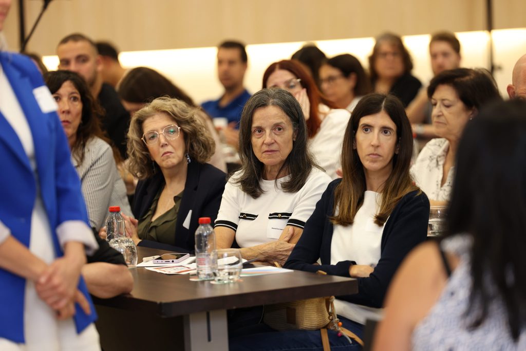 People seated at a table: Attendees seated at a table listen closely to a speaker.