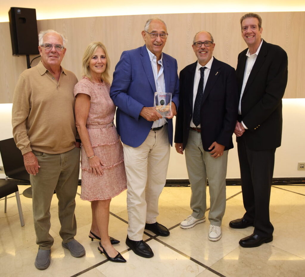 Michael L. Weamer, Eileen Novins, el Dr. Arturo Evangelista con el Premio Antoine Marfan, Gustavo Egea, PhD, y Bert Medina posan juntos en una sala de reuniones.