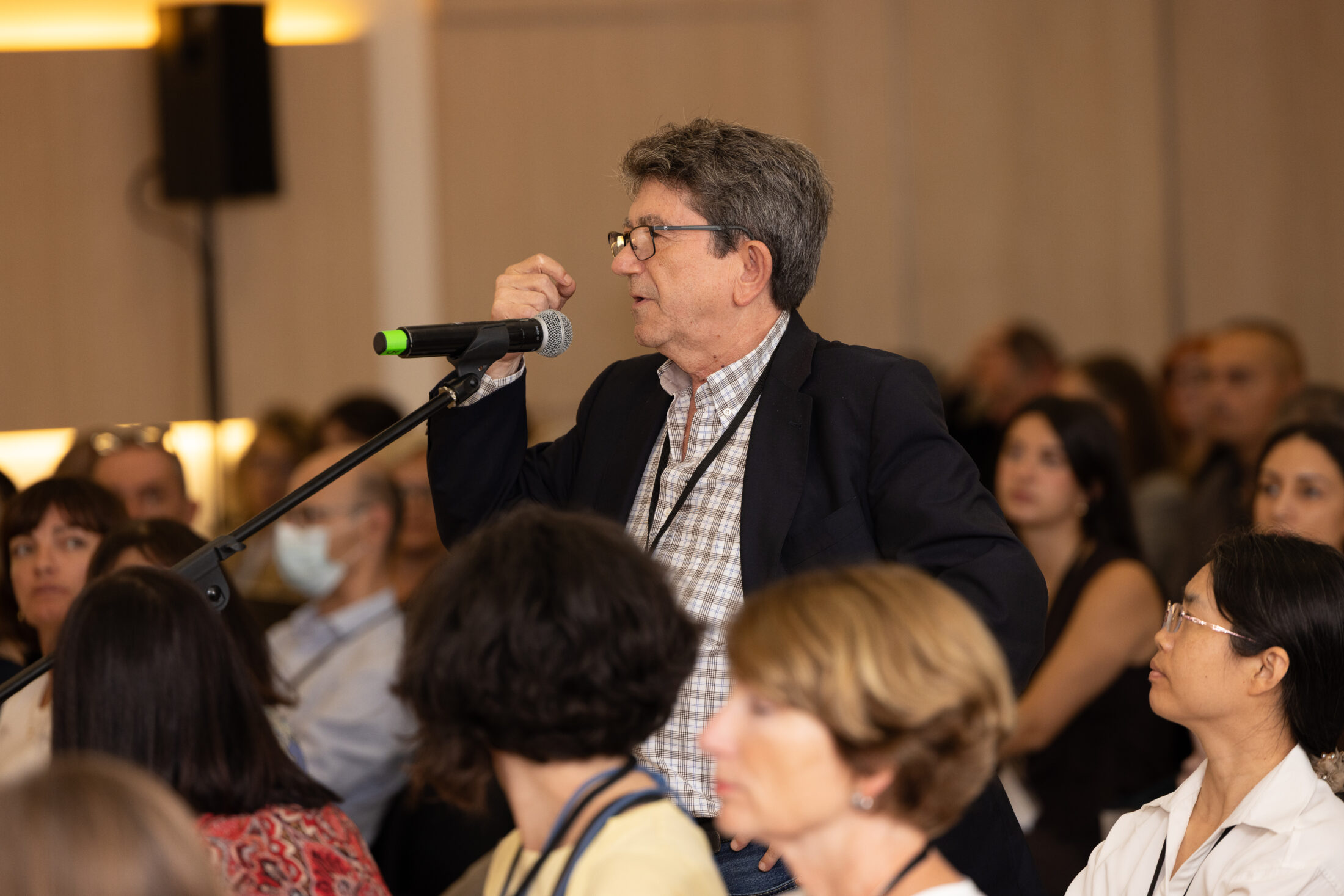 Scientist stands, asks question amid large seated crowd during Science in Spain
