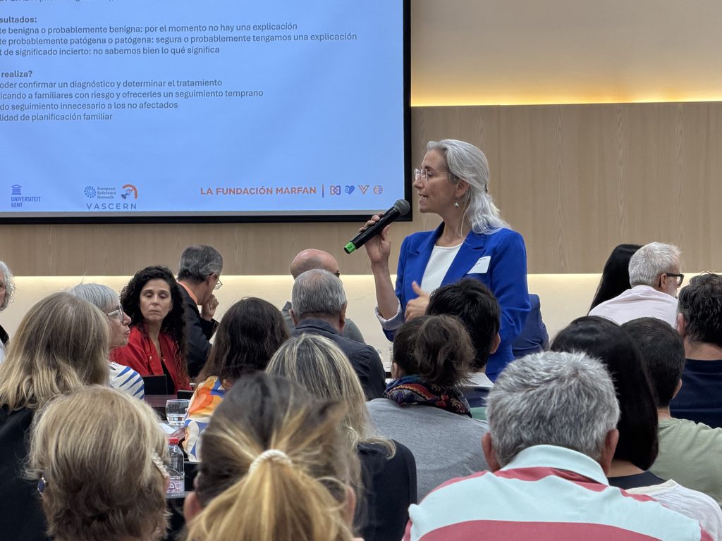 La Dra. Laura Muiño Mosquera habla por micrófono delante de una diapositiva sobre los resultados de las pruebas genéticas.